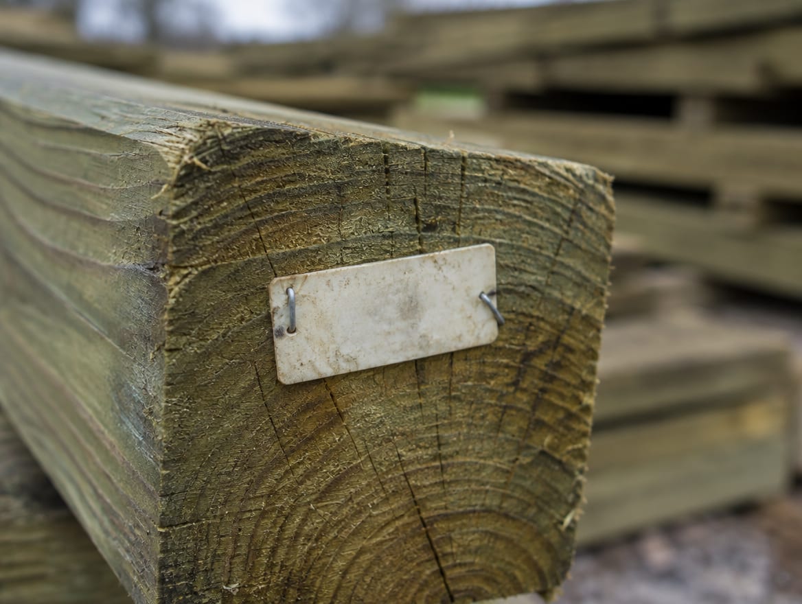 Plastic end tag stapled to the end of a pressure-treated post
