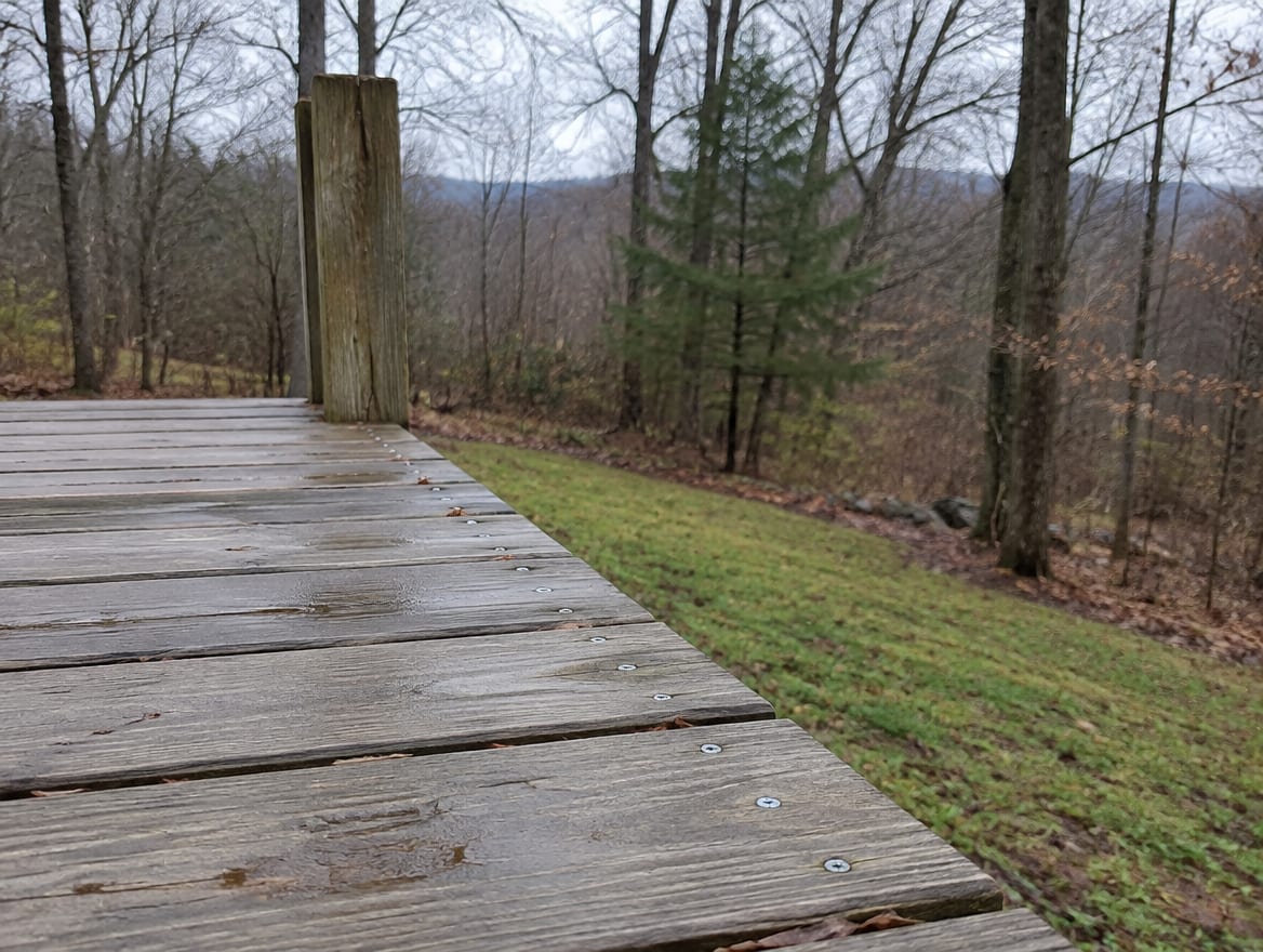 Open edge of a raised deck with no guard installed and a drop to the ground below