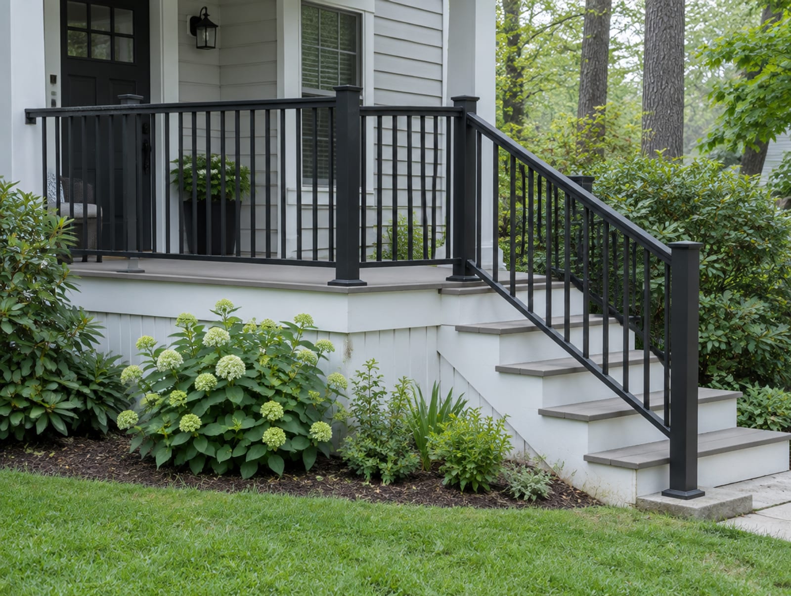 Completed black aluminum railing across the front of a porch and down its steps