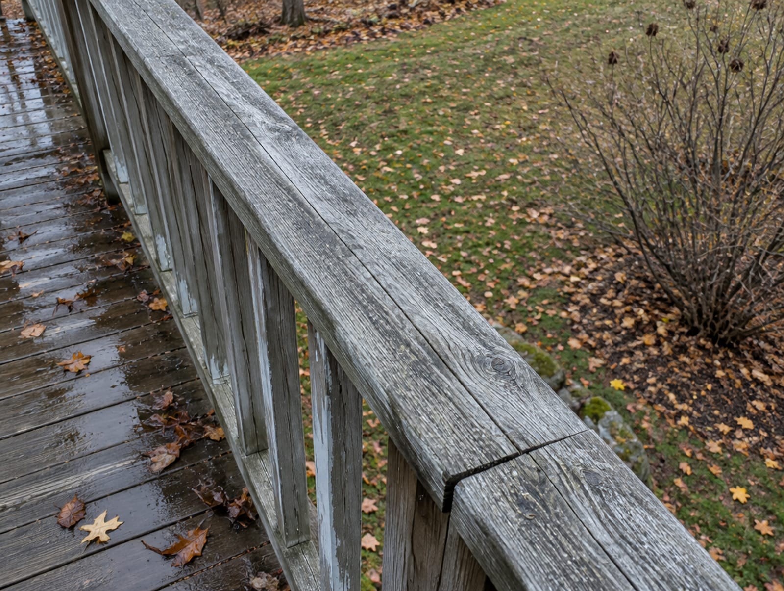 Front porch with steps and a low older wood railing, the porch floor several feet above the lawn