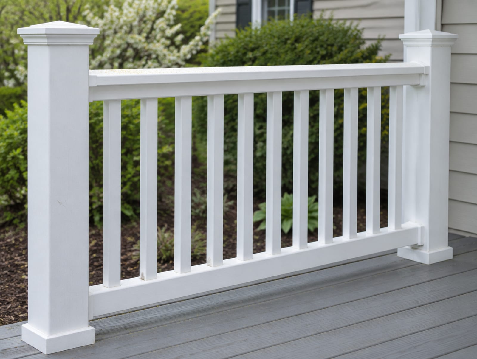 Section of white vinyl porch railing with square posts, a top rail and vertical balusters