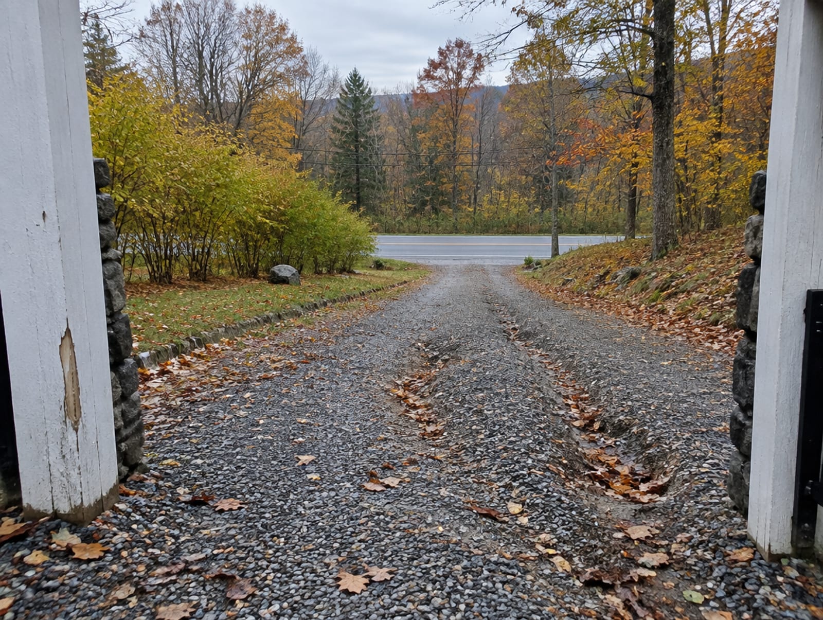 Gravel driveway rising slightly toward a gate opening between two posts