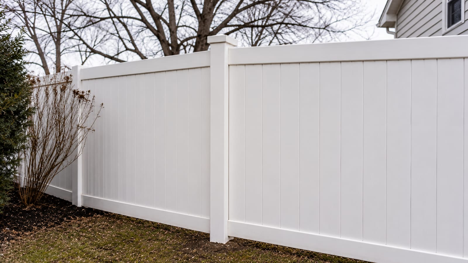 Tall white vinyl privacy fence panels enclosing a backyard